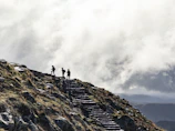 person standing on rocky mountain under cloudy sky during daytime
