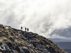 person standing on rocky mountain under cloudy sky during daytime