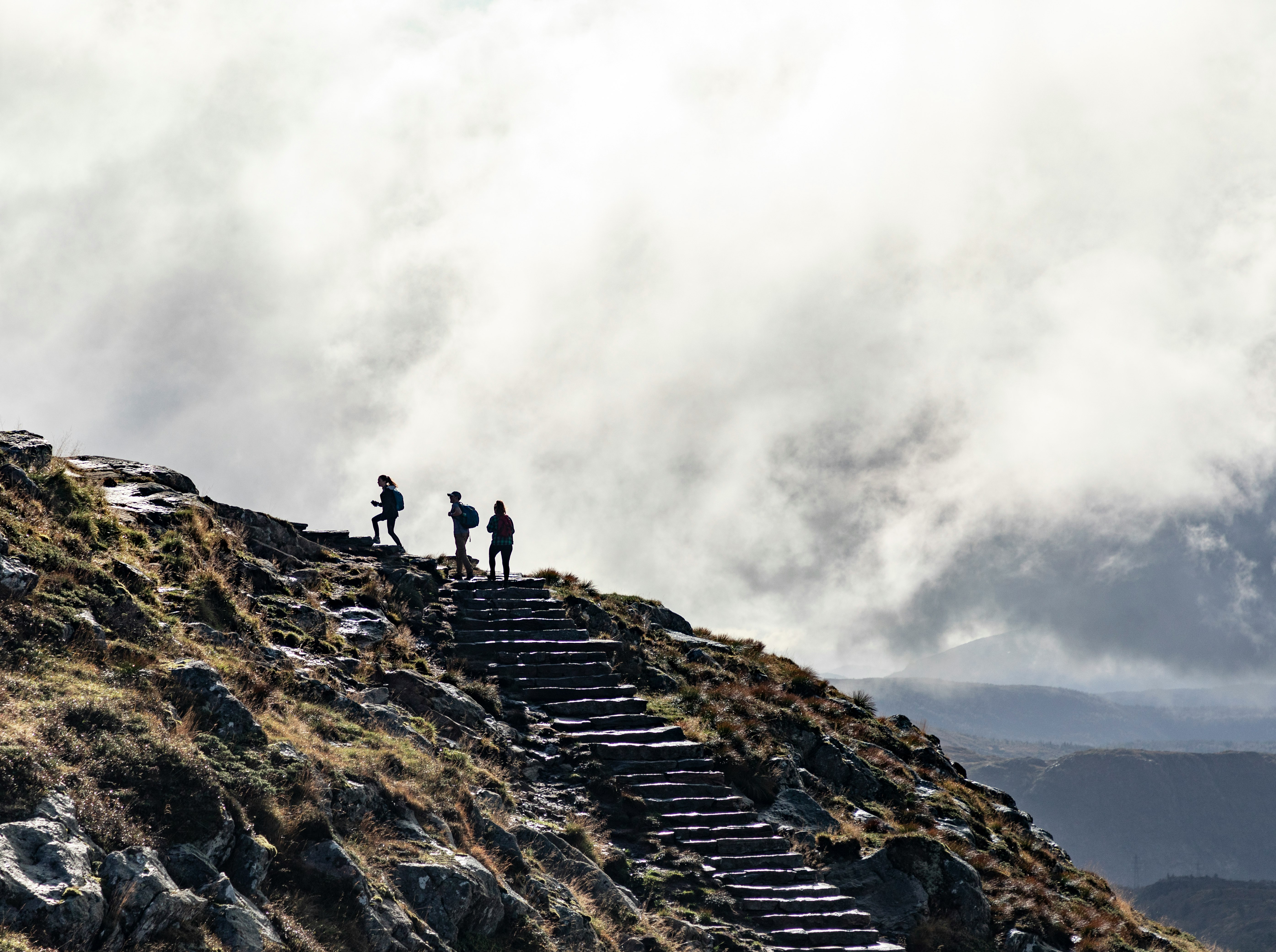 person standing on rocky mountain under cloudy sky during daytime