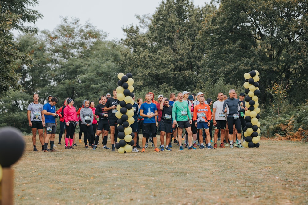 people in green and black shirts standing on brown field during daytime