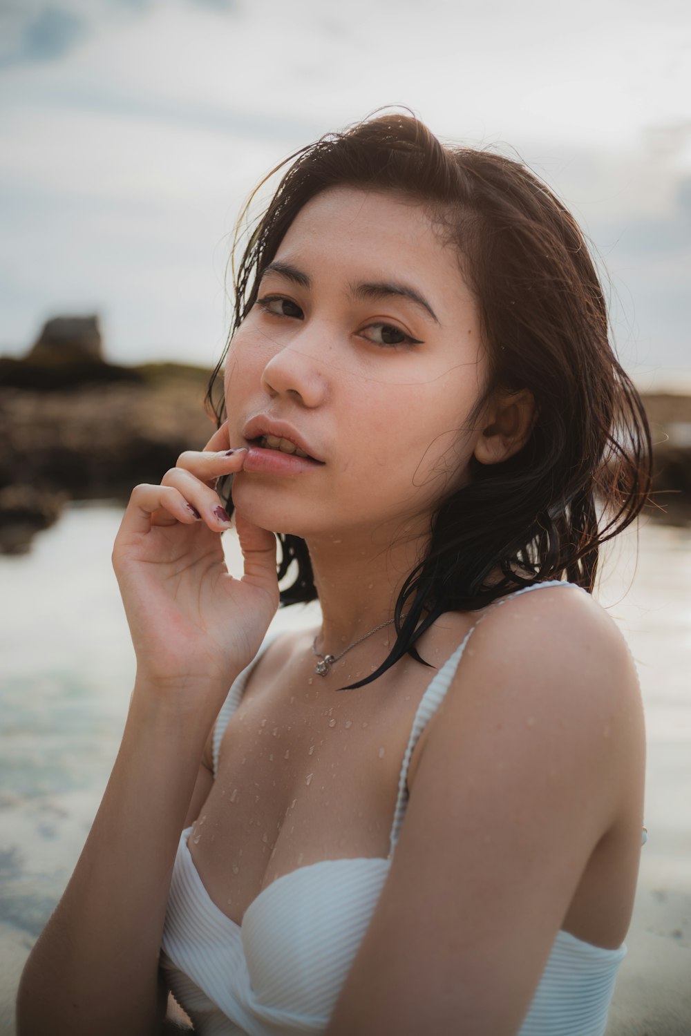 girl in white tank top standing on beach during daytime