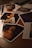 A collection of photographs scattered on a wooden surface, capturing various portraits and scenes. The lighting is dim, providing a warm and moody atmosphere.