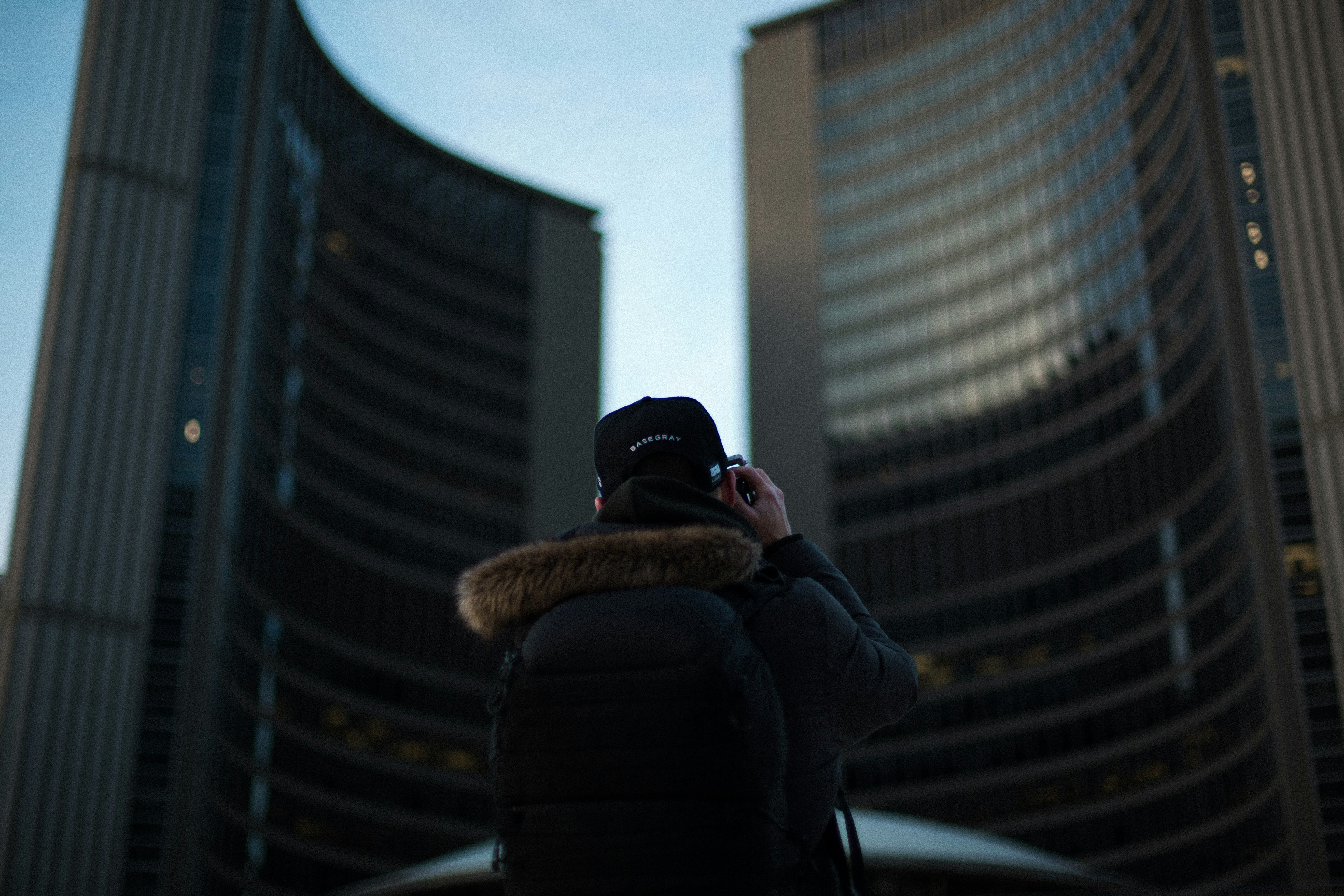 man in black jacket and black cap standing near building during daytime