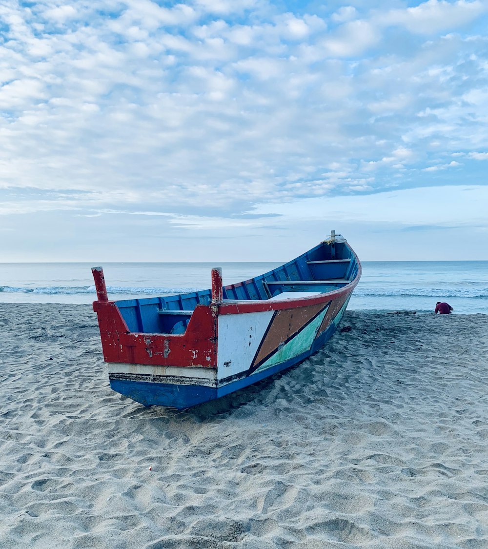 blue and red boat on beach during daytime