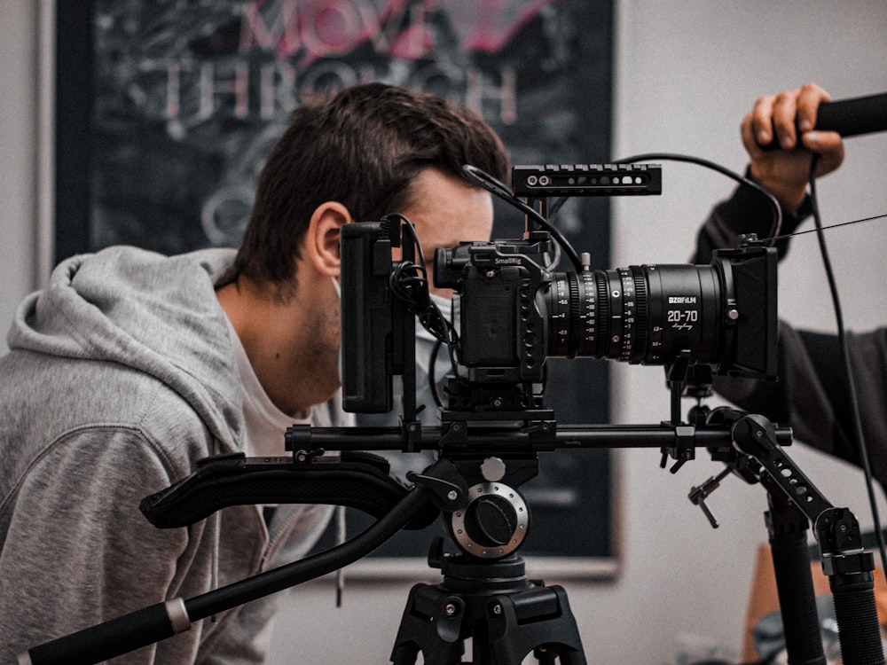 man in gray hoodie holding black video camera