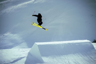 man in black jacket and yellow pants riding yellow snowboard on snow covered ground during daytime