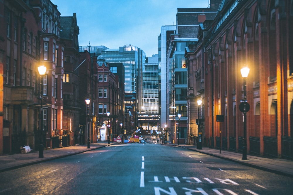 cars on road between high rise buildings during night time