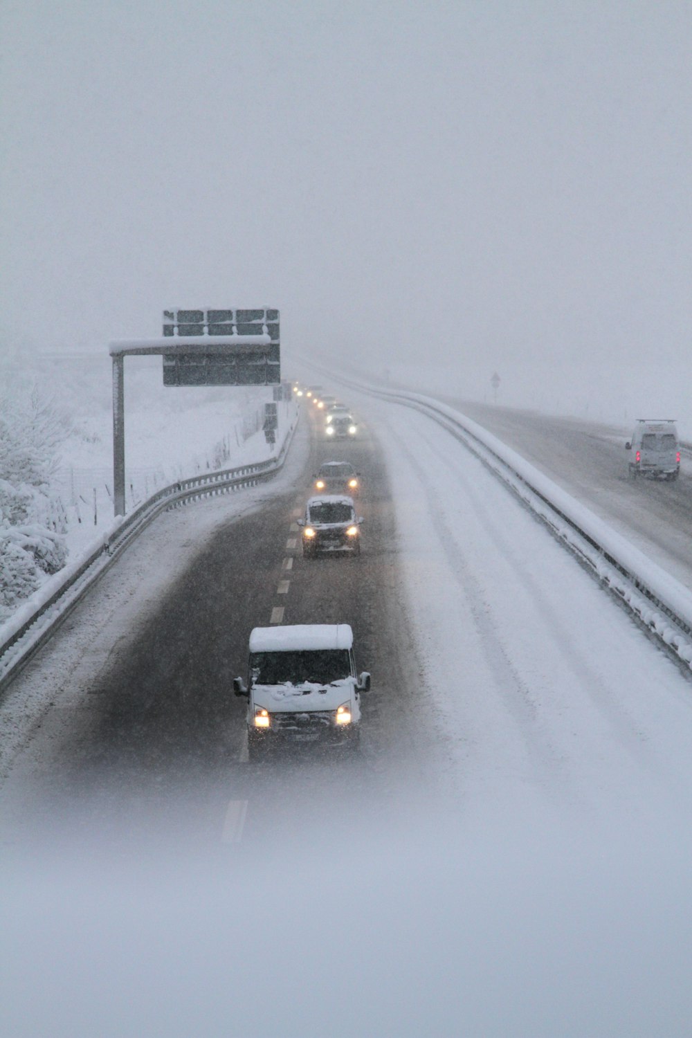 black car on road covered with snow during daytime