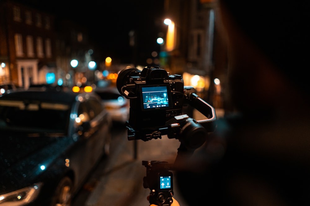 person holding black dslr camera taking photo of street during night time