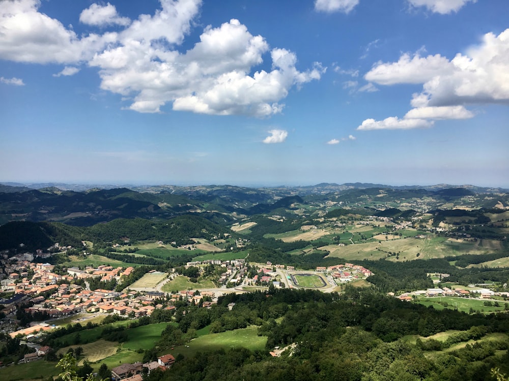 alberi e case verdi sotto il cielo blu e le nuvole bianche durante il giorno