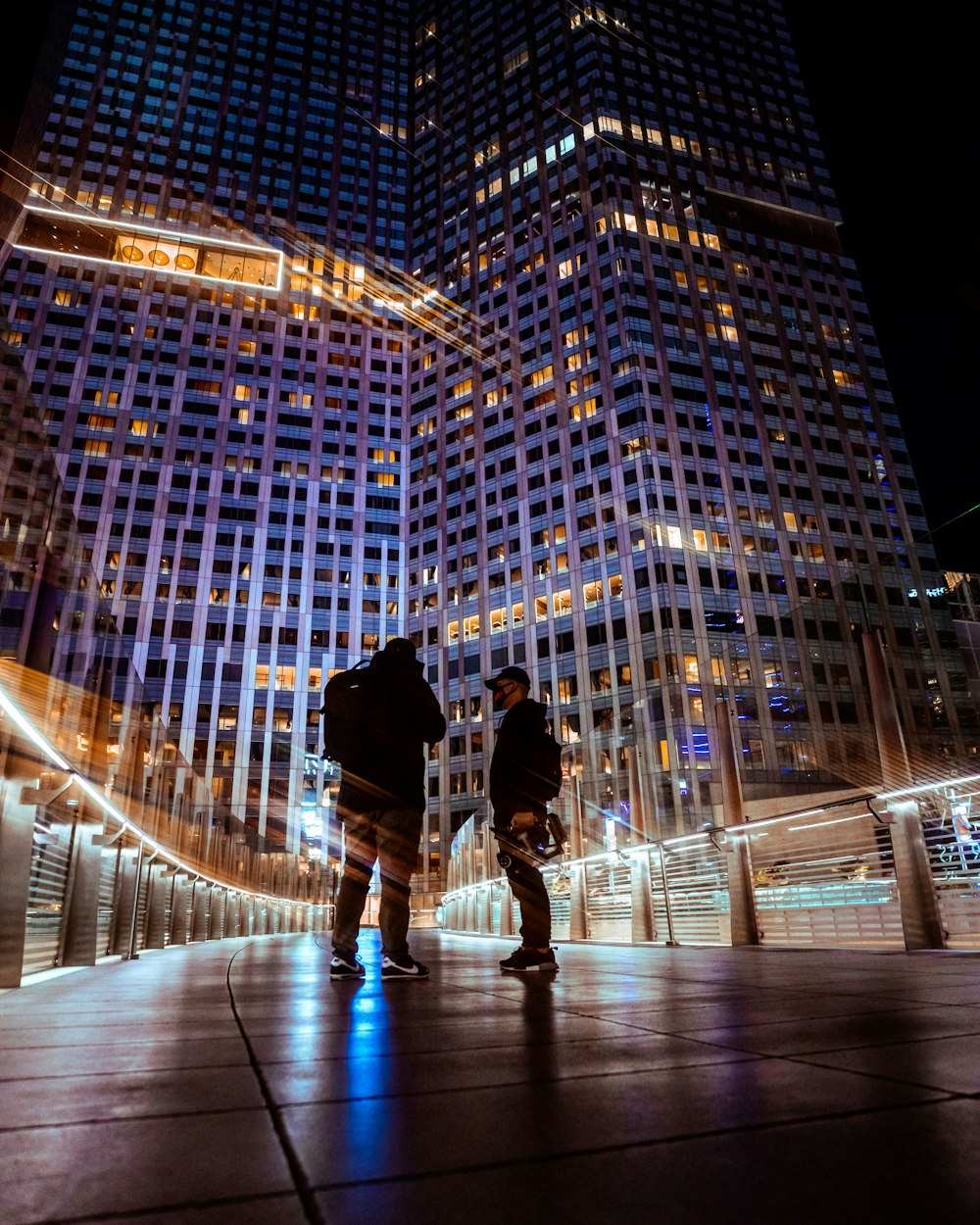 man in black jacket and blue denim jeans walking on street during night time