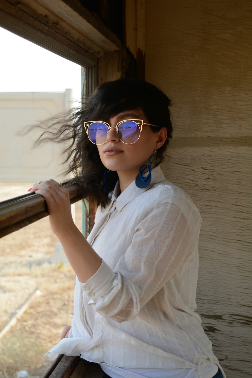 woman in white button up shirt wearing blue sunglasses