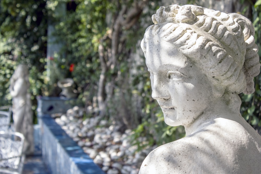 Statue en béton blanc près des arbres verts pendant la journée