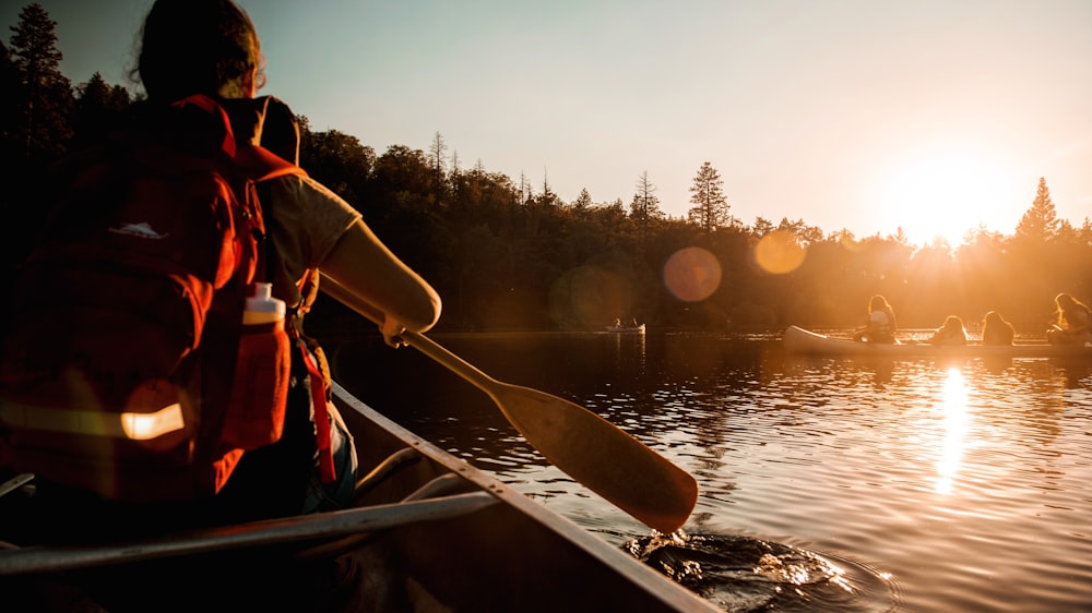 man in red and black jacket riding on boat during sunset