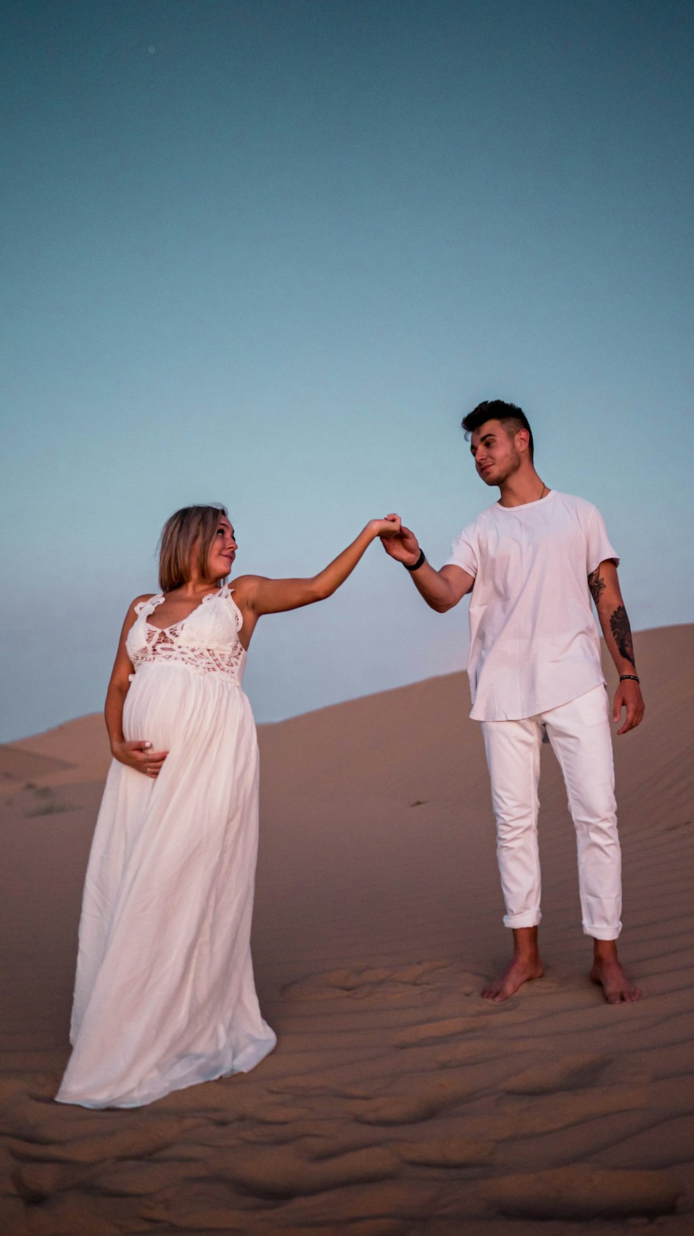 man and woman holding hands while walking on beach during daytime