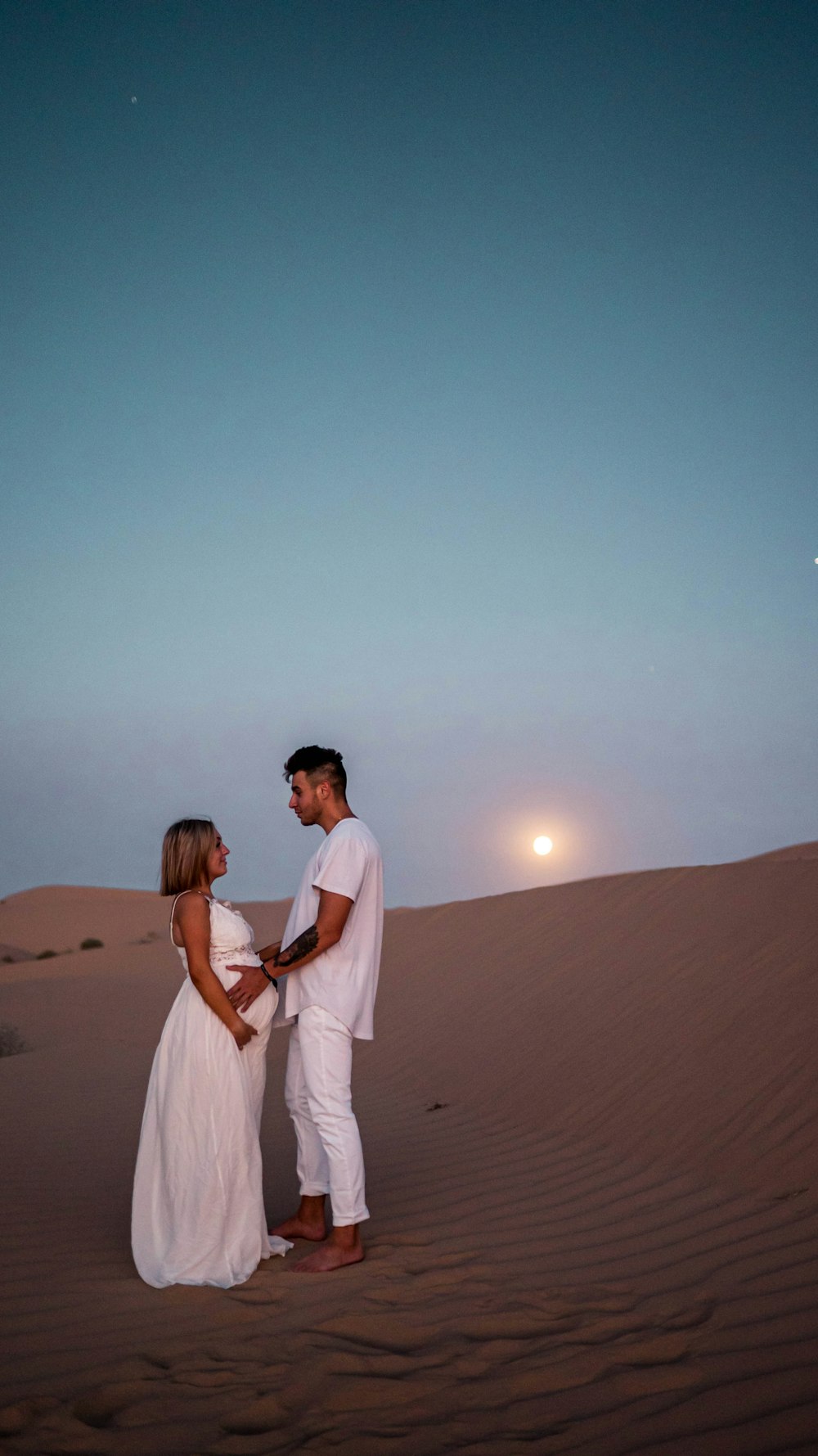 man and woman kissing on sand during daytime