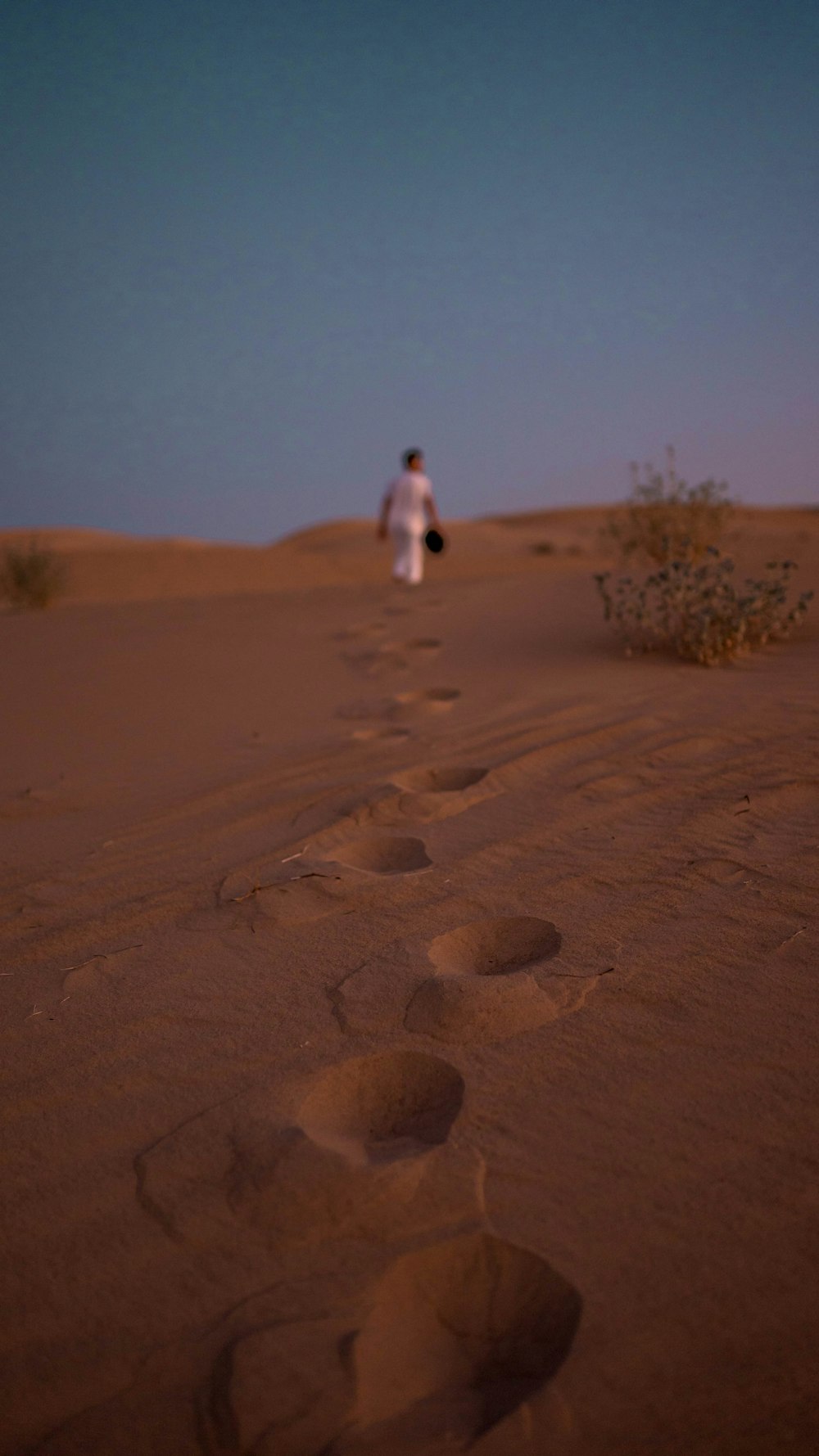 person in white shirt walking on brown sand during daytime