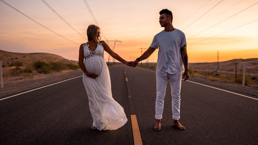 man and woman holding hands while walking on road during daytime