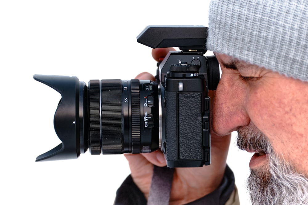 hombre con gorra de punto gris sosteniendo una cámara réflex digital negra