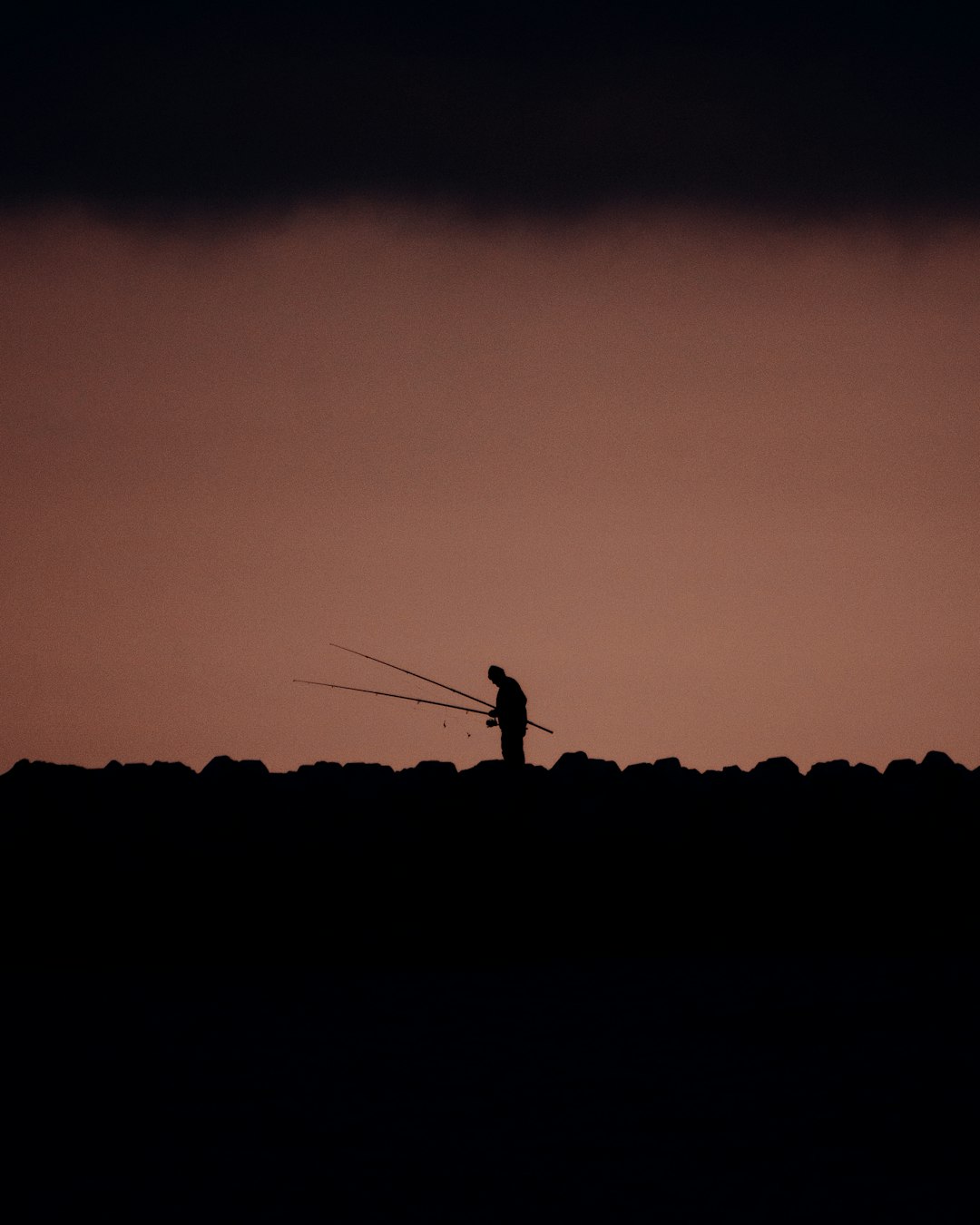 silhouette of person standing on top of mountain during sunset