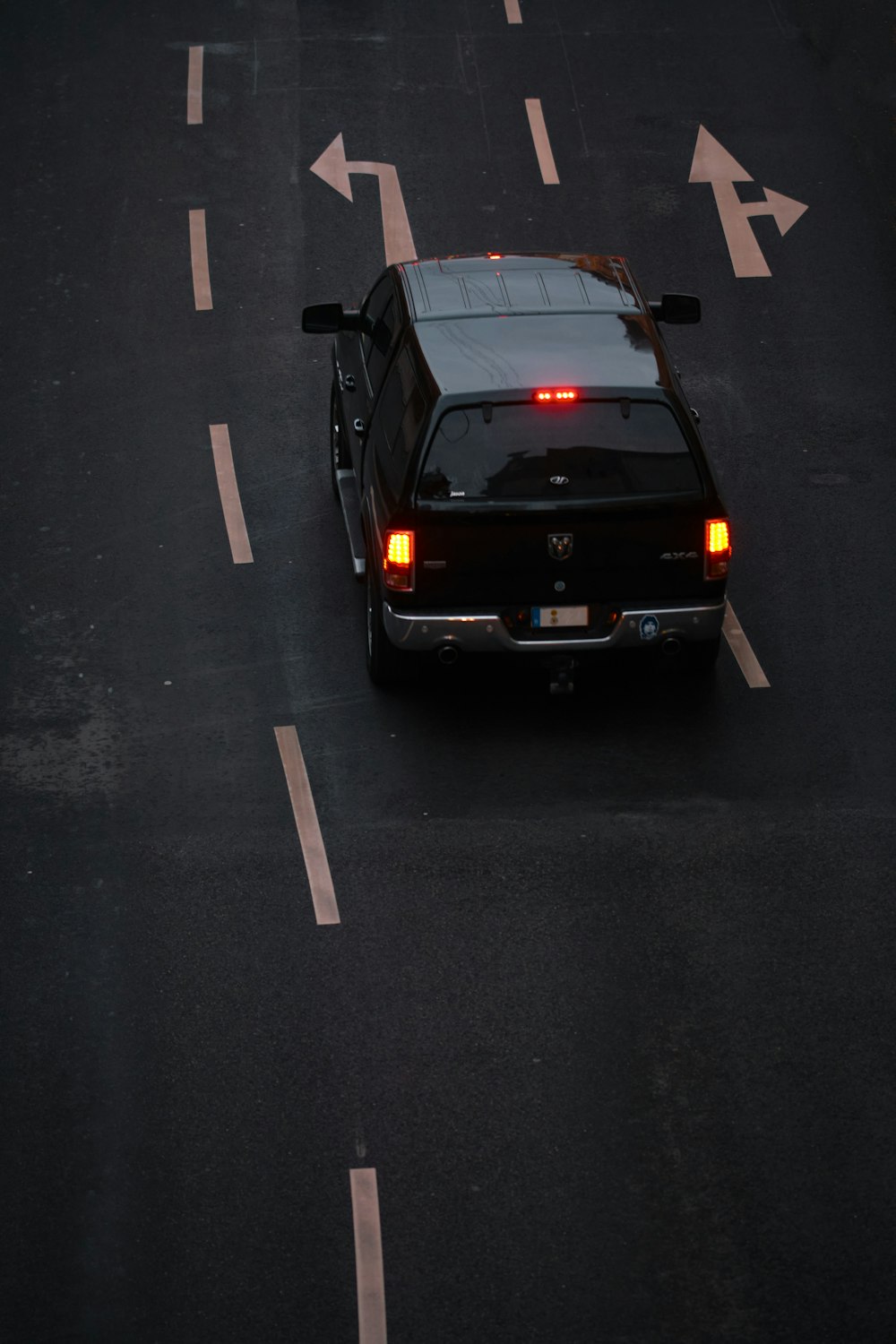 昼間の黒いアスファルト道路を走る黒い車