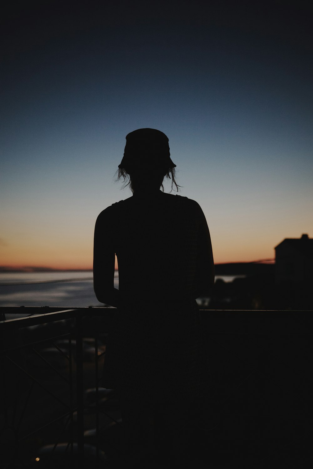 silhouette of woman standing near railings during sunset