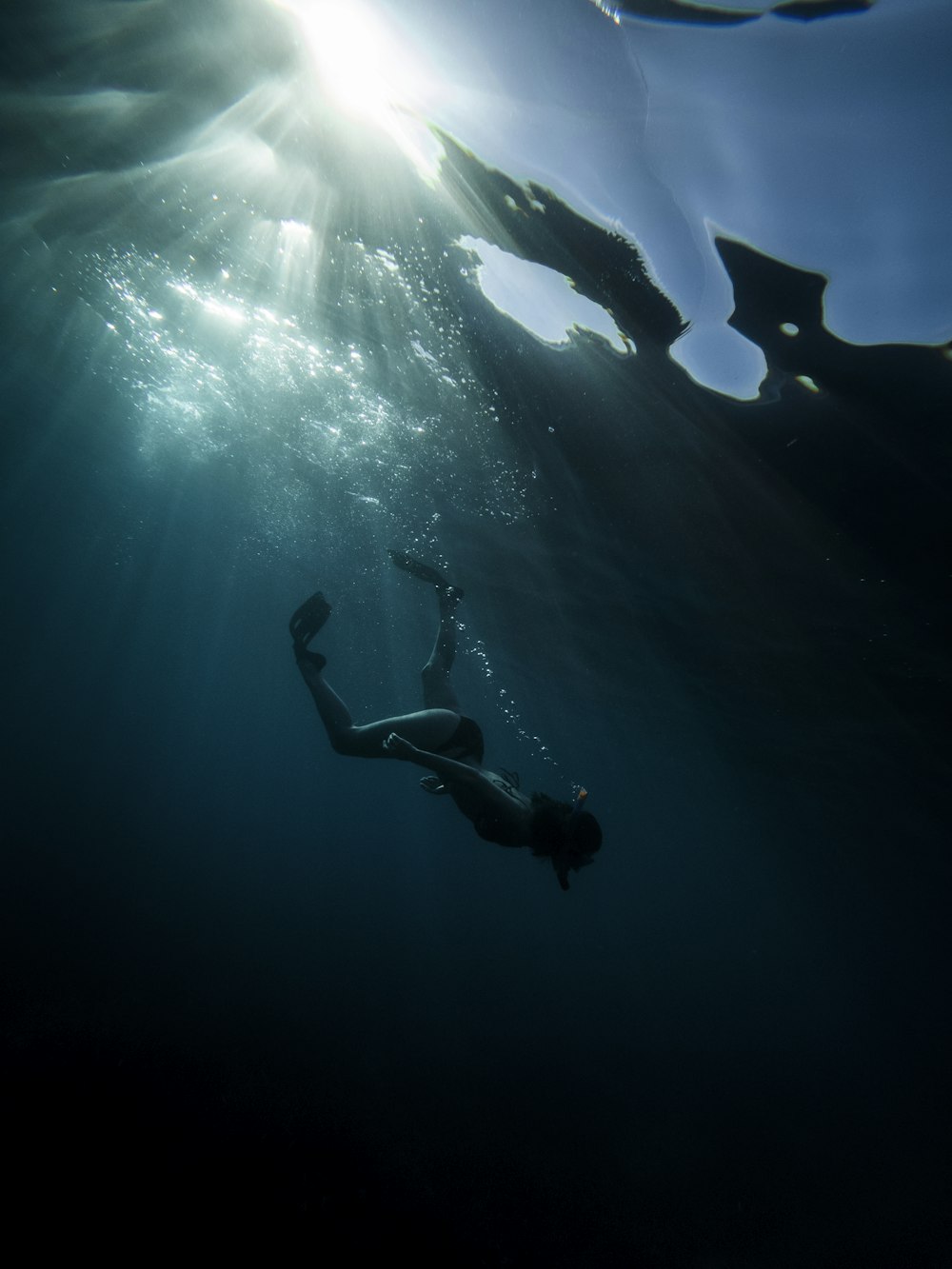 Hombre en pantalones cortos negros buceando en el agua