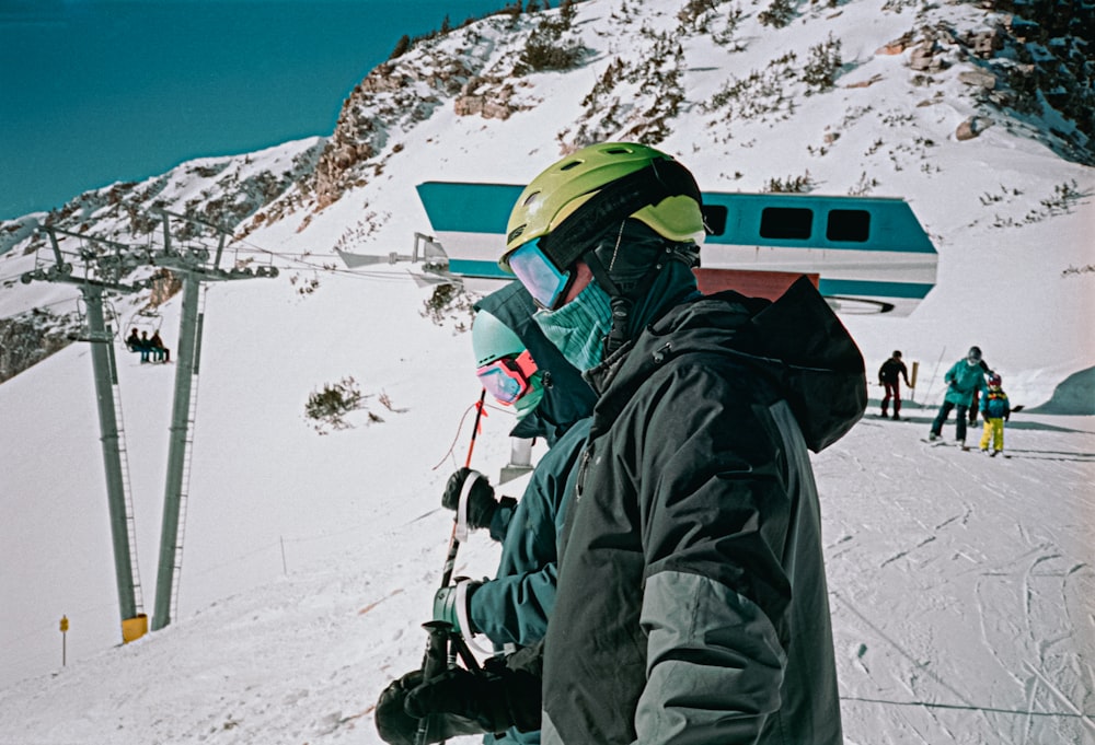 Persona con chaqueta negra y casco verde en la montaña cubierta de nieve durante el día