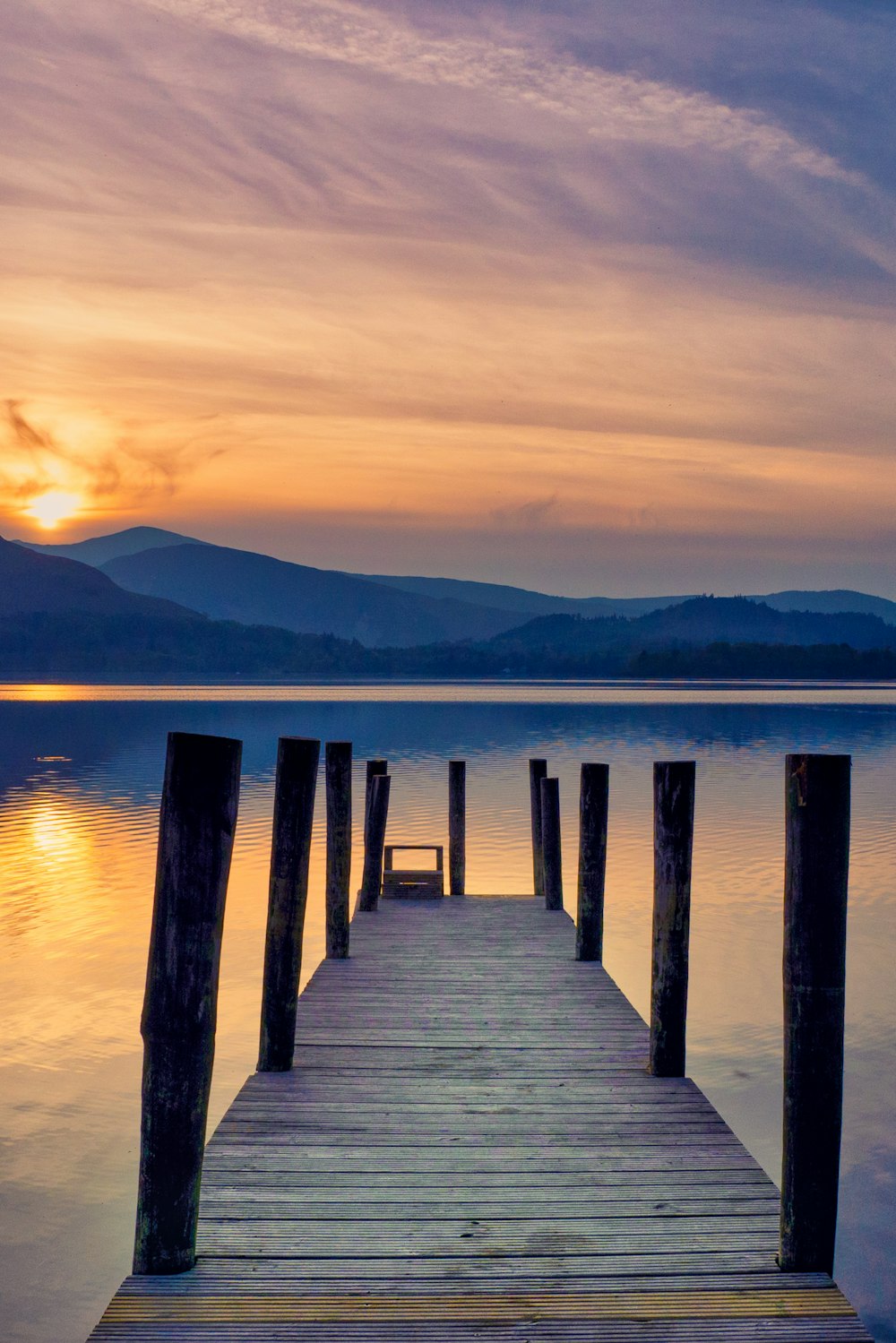 brown wooden dock on lake during sunset