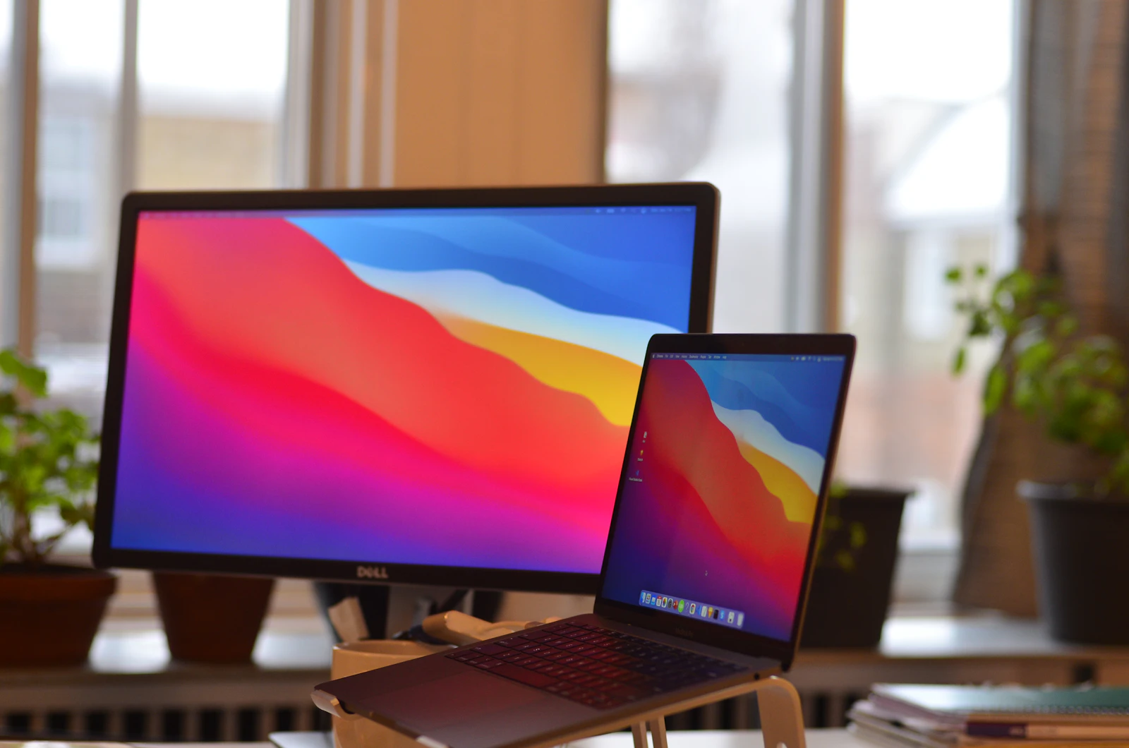 Espacio de trabajo minimalista con un Apple MacBook Pro abierto y un cuaderno sobre un escritorio de madera oscura