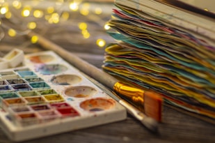 watercolor palette with a stack of colored papers