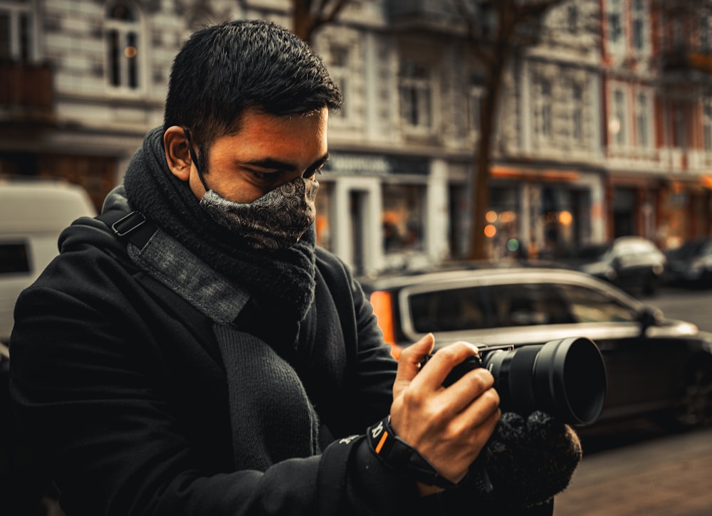 man in black jacket holding black camera