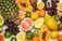 A vibrant assortment of fresh fruits including pineapples, papayas, grapes, oranges, grapefruits, lemons, avocados, kiwis, and limes. The fruits are arranged randomly, showcasing varying colors and textures on a light background.