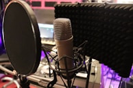 A microphone setup in a cozy recording booth surrounded by acoustic panels.