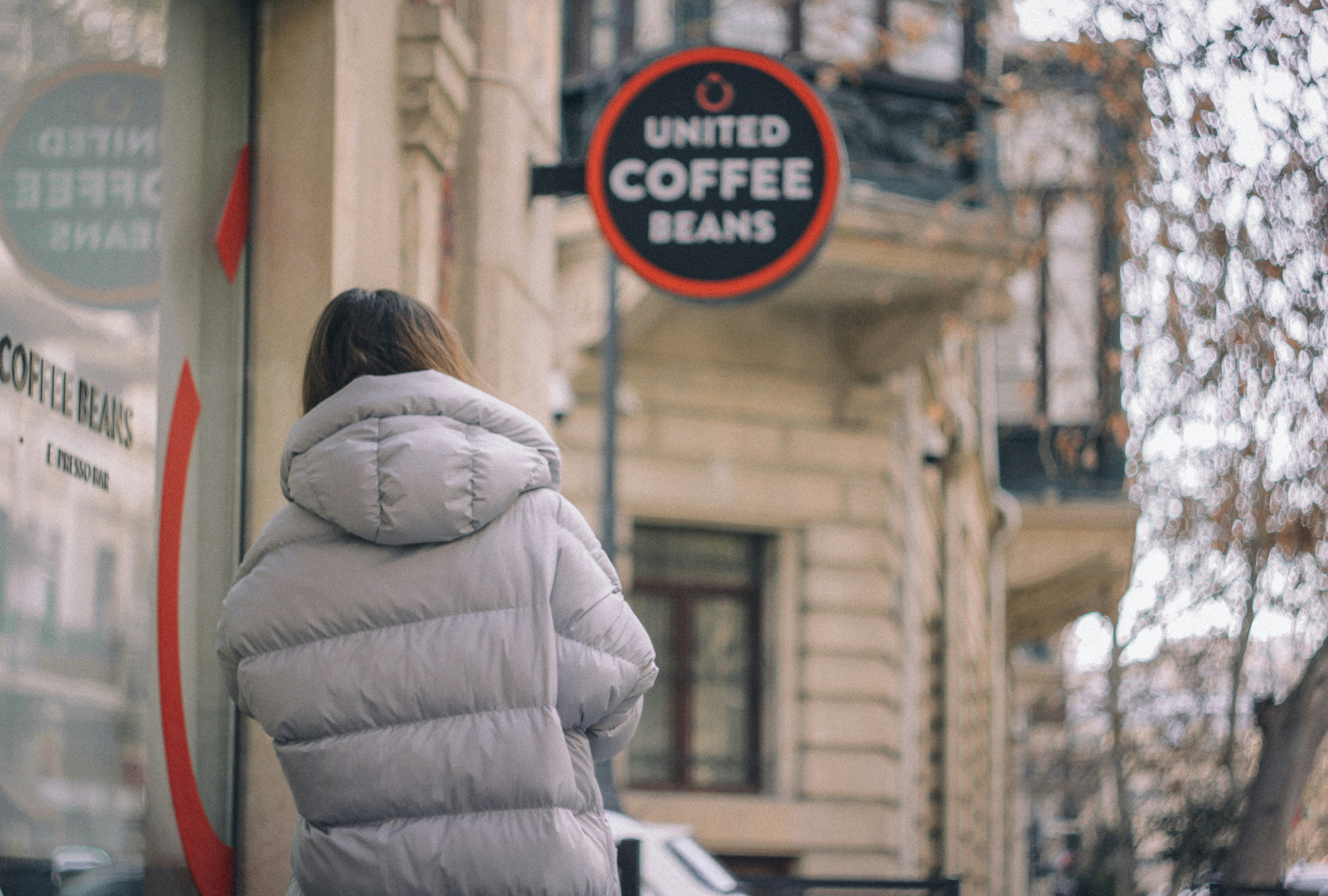 woman in white fur coat standing near red and white signage