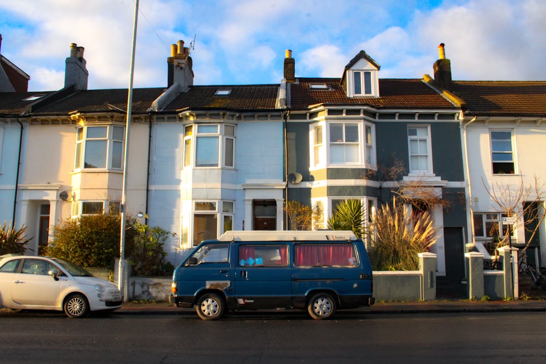 blue van parked in front of white concrete building during daytime