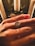 A hand is adorned with an elegant teardrop-shaped diamond ring. The background features candles and decorative greenery, suggesting a festive or intimate setting. The lighting creates warm hues on the skin and highlights the sparkle of the diamond.