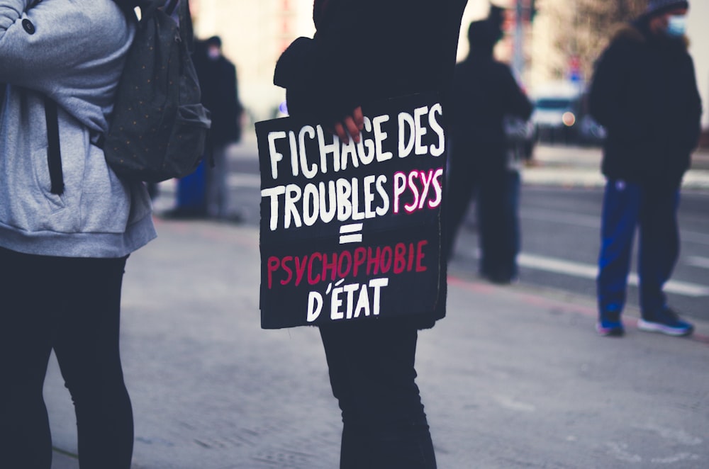 a woman holding a sign on the side of the road