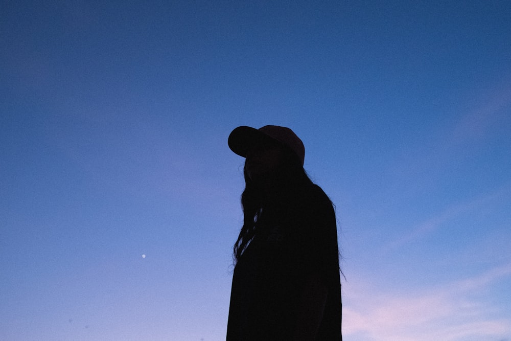 silhouette of woman wearing hat under blue sky during daytime