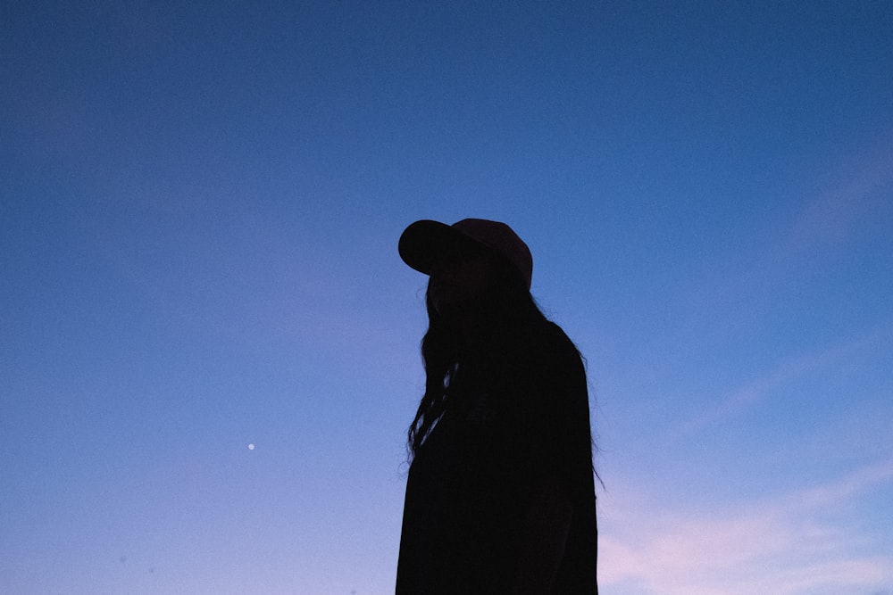 Silueta de mujer con sombrero bajo el cielo azul durante el día