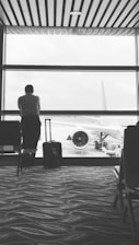 A happy traveler holding a plane ticket with a suitcase at the airport.