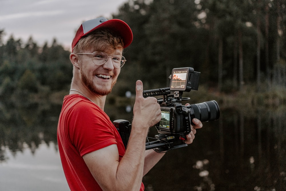 man in red crew neck t-shirt holding black video camera