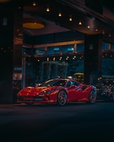 A glossy red sports car parked under moody lighting highlighting its polished finish.