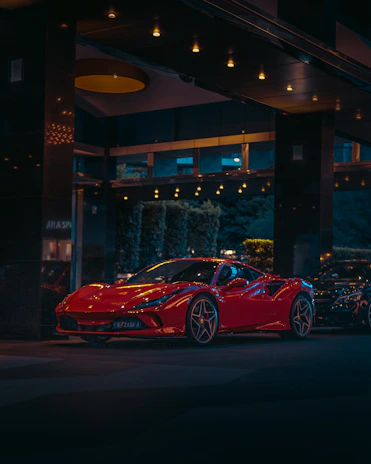 A polished sports car parked in front of a modern building under soft golden lighting.