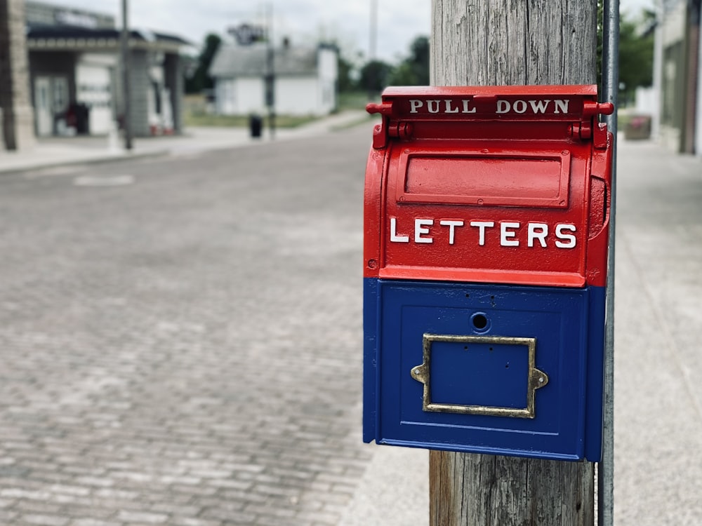 Boîte aux lettres rouge sur poteau en bois brun