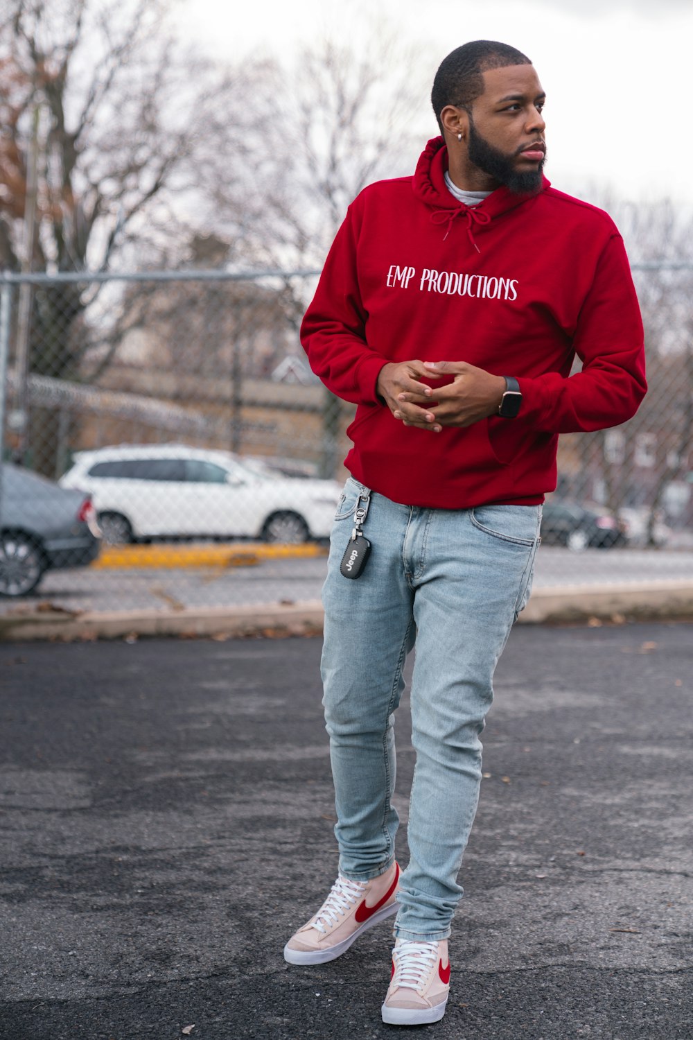 man in red hoodie and blue denim jeans standing on road during daytime