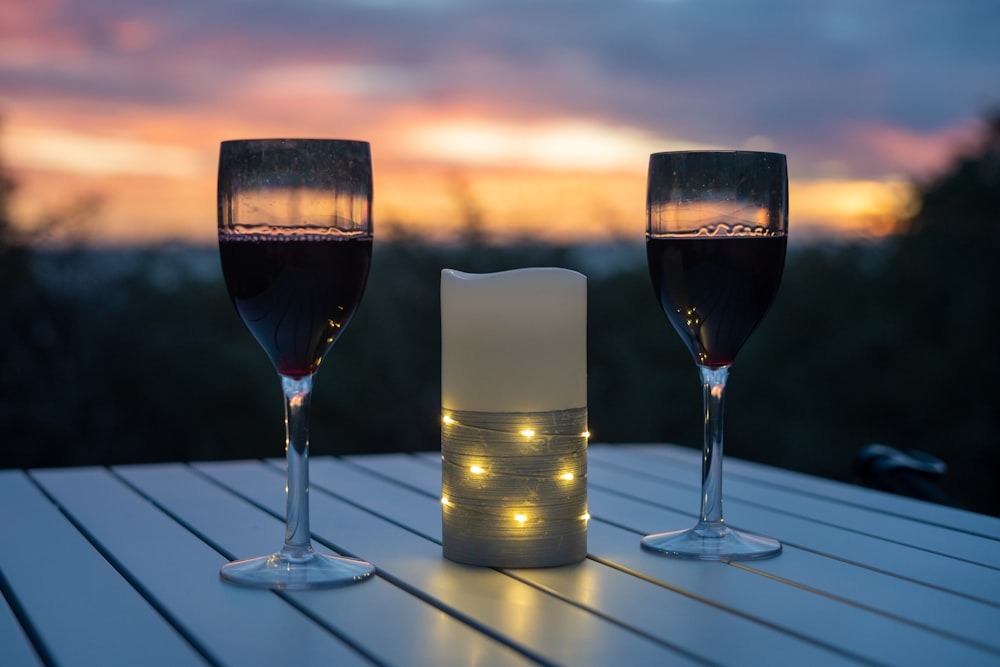 clear wine glass with red wine beside clear glass bottle on table