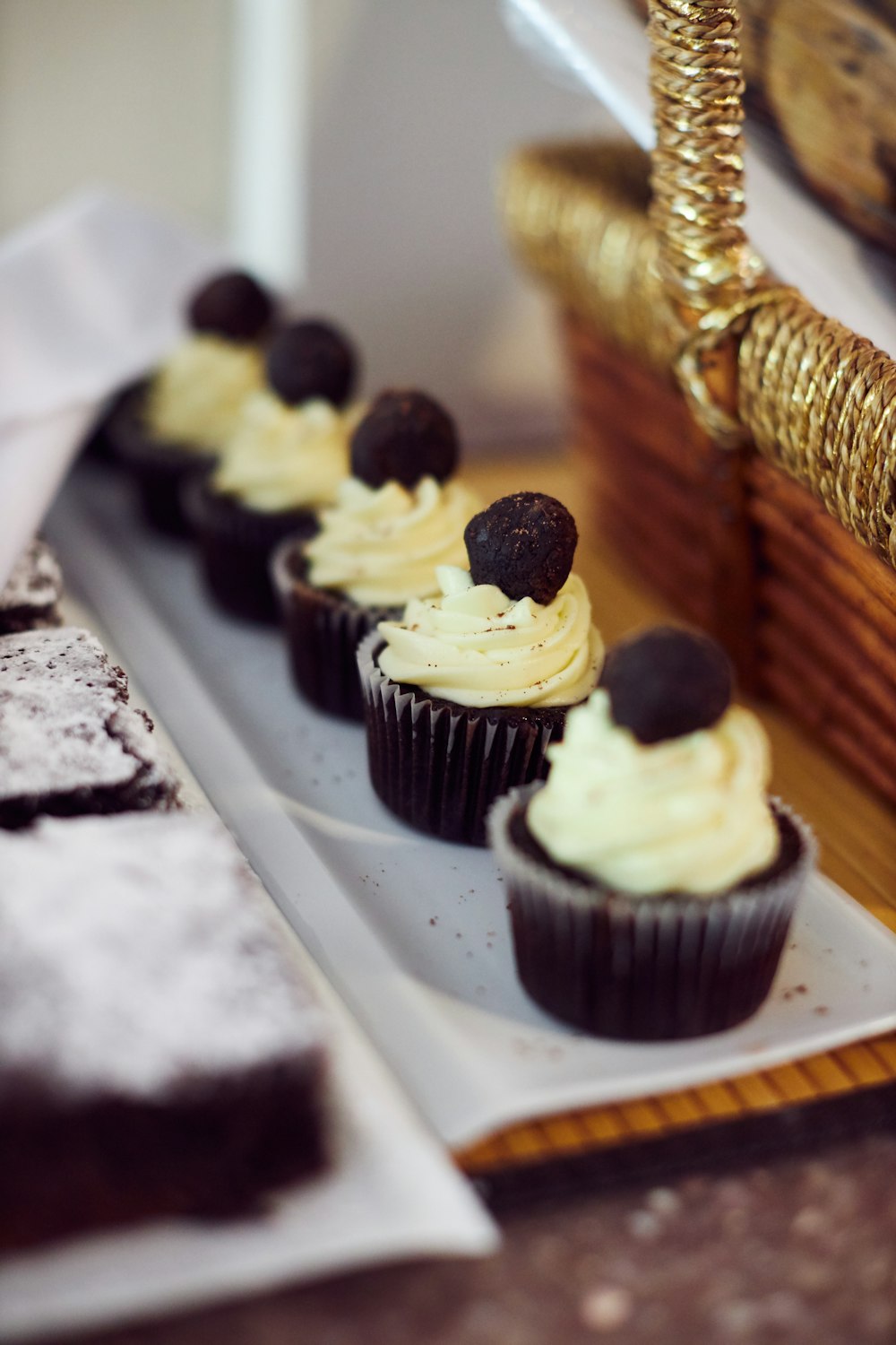white and black cupcakes on brown wooden tray