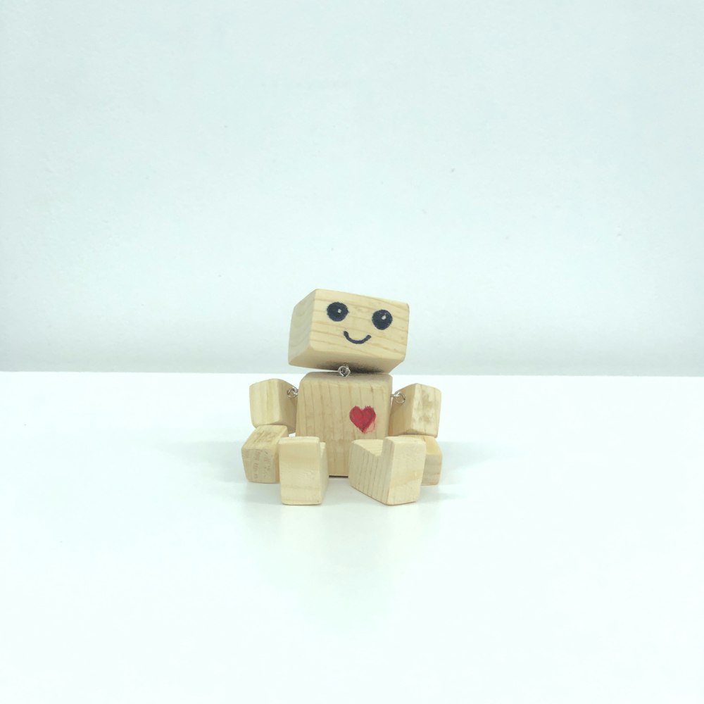 jouet robot en bois brun sur surface blanche