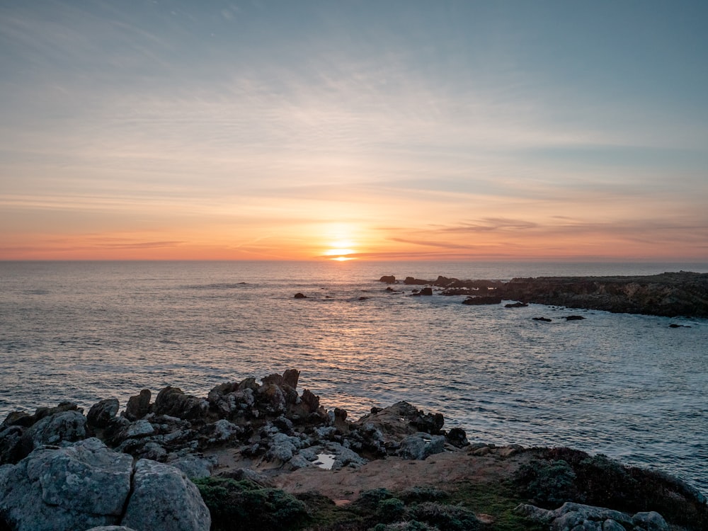 gray rocks on sea shore during sunset
